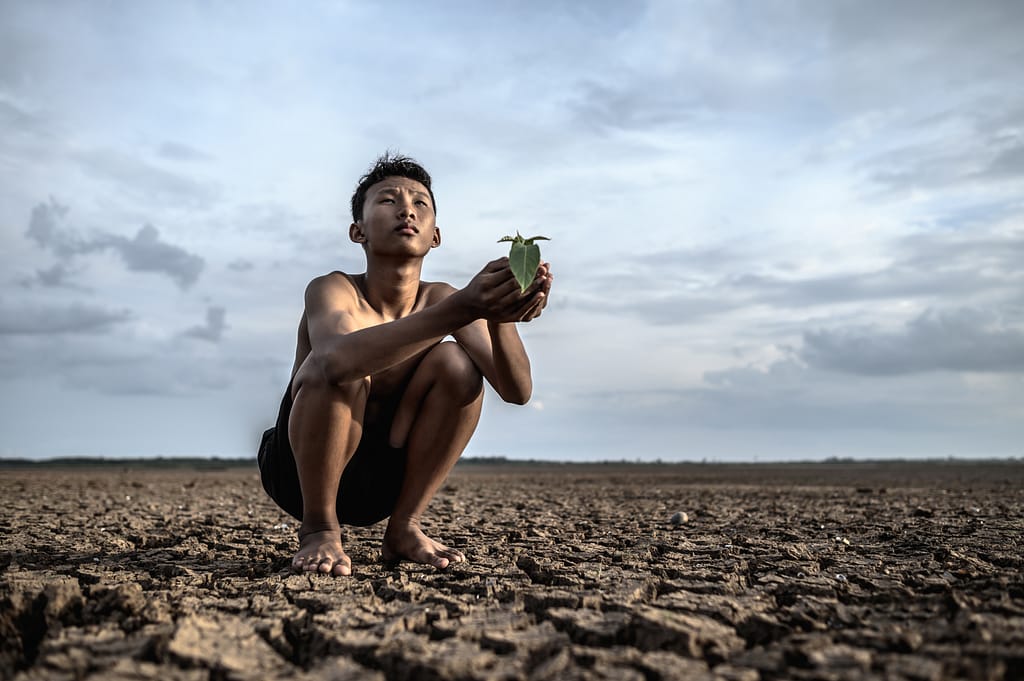 A boy sitting in drought landscape